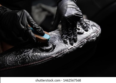 Man Worker Of Car Wash Cleaning Leather Car Seat With Brush And Detergent. Cleaning Car Interior