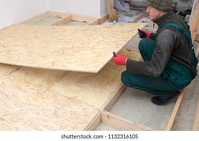 Man Worker Fits Wooden Oriented Stands Bords On Insulated Floor. New House Constuction