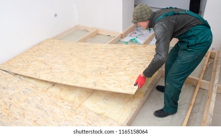 Man Worker Fits Wooden Oriented Stands Bords On Insulated Floor. New House Constuction