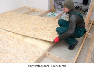 Man Worker Fits Wooden Oriented Stands Bords On Insulated Floor. New House Constuction