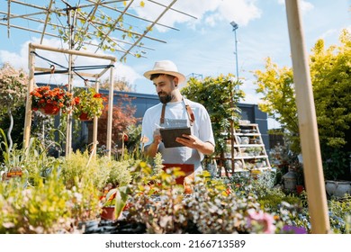 Man Worker In Garden Centre. Using Tablet. Gardener