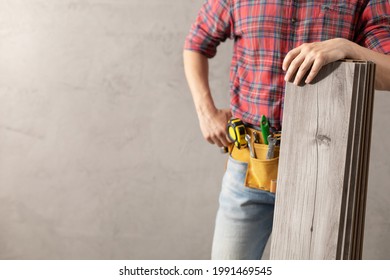 Man Worker Holding  Laminate Floor Plank And Tool Belt . Male Hand And Construction Tools. Renovation Or Repair Concept