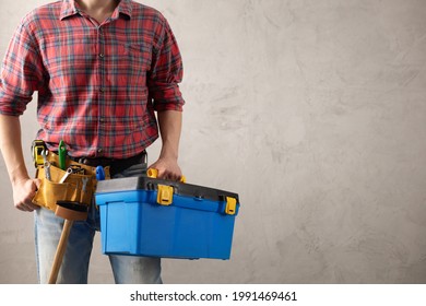Man worker holding toolbox and tool belt near wall. Male hand and construction tools. Renovation or repair concept