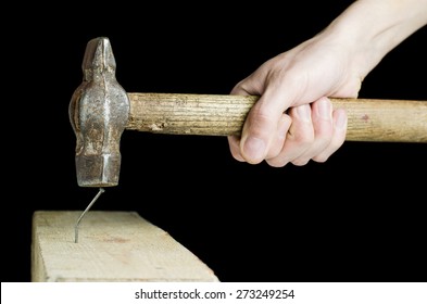 The man worker is making failed attempt to hammer the nail in the wooden bar.