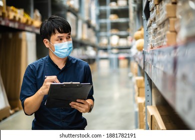 Man Worker With Medical Mask Holding Clipboard And Checking Inventory In The Warehouse During Coronavirus (covid-19) Pandemic