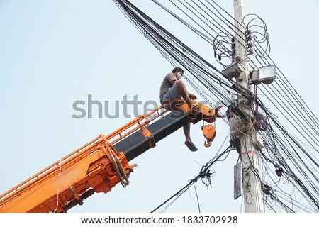 Man, worker on top of crane tractor for maintenance electric cables without safety belt is risk work. Concept of unsafe work place, risk work, unsafe work.                              