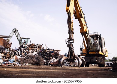 Man worker operating scrap metal recycling machine in junk yard. - Powered by Shutterstock