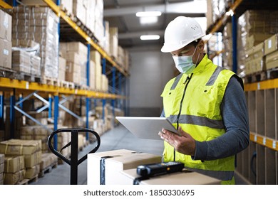 Man worker with tablet working indoors in warehouse, coronavirus concept.