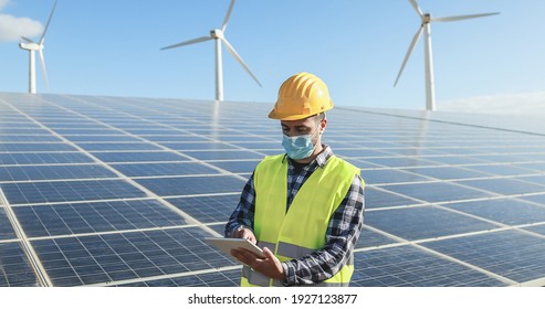 Man Worker Using Digital Tablet While Wearing Safety Mask At Renewable Energy Farm During Coronavirus Outbreak - Soft Focus On Face