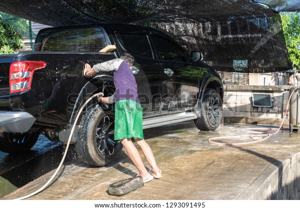Man worker wash car. Car washing using high\
pressure water and sponge.