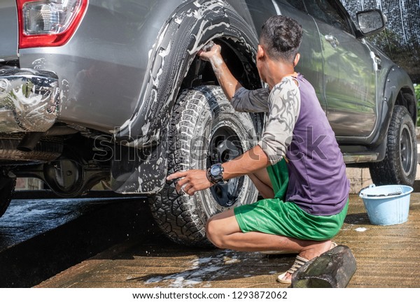 Man worker wash car. Car washing using high\
pressure water and sponge.
