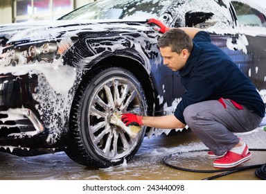 Man worker washing car's alloy wheels on a car wash 