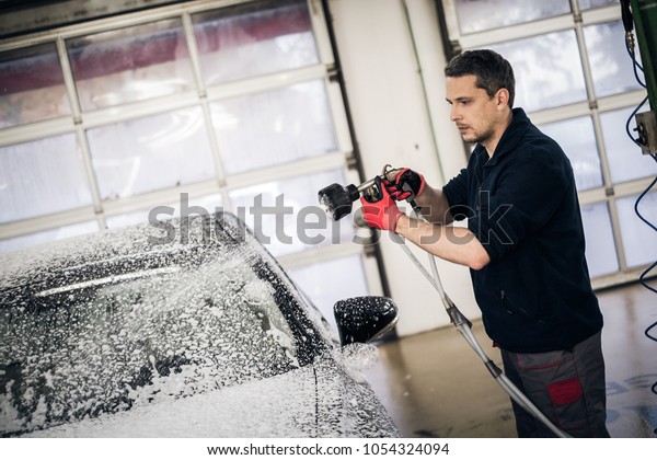 Man worker\
washing luxury car on a car\
wash.
