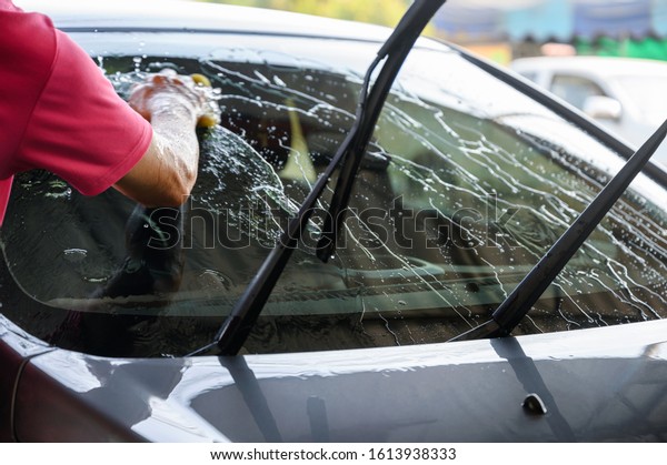 Man\
worker washing and rubbing car with sponge and\
water