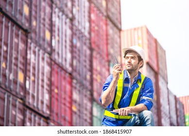 Man Worker Wears White Hardhat And Reflection Shirt, Holds Walkie Talkie And Checklist Clip Board For Commanding With Metal Containers In Background. Logistic And Transportation Management Concept.