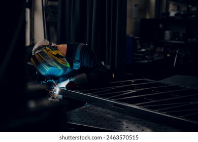 Man worker working with a metal product and welding it with a arc welding machine in a workshop. Industrial manufacturing. Welding metal part in a factory. - Powered by Shutterstock