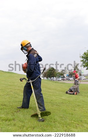 Man workers city landscapers starting gas trimmer and lawn mower equipment  