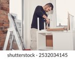 Man working and assembling furniture in a new apartment.