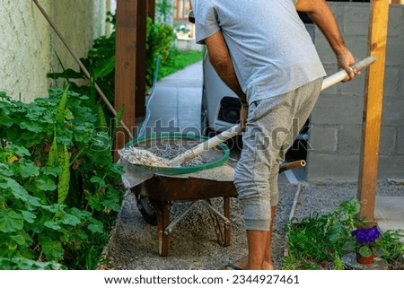 Similar – A skilled craftsman engaged in a hands-on outdoor task, carefully raking and maintaining a garden area