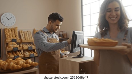 Man working at a bakery counter while a woman carries fresh bread in a warmly lit, modern bakery interior filled with an assortment of breads and pastries - Powered by Shutterstock