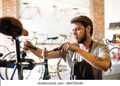 A Man Working In A Bicycle Repair Shop, Checking The Frame Of The Bike