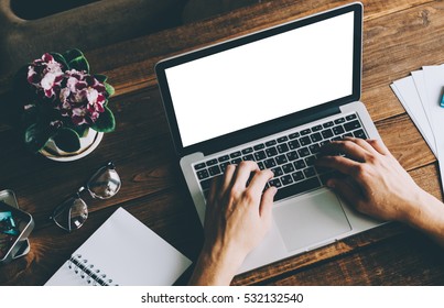 A Man Is Working By Using A Laptop Mockup Computer On Vintage Wooden Table. Hands Typing On A Keyboard. Top View.
