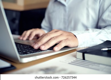 Man arbeitet mit einem Laptop auf einem Holztisch. Hände, die auf einer Tastatur tippen.