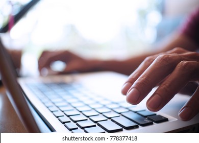 Man working by using a laptop computer on wooden table. Hands typing on a keyboard. - Shutterstock ID 778377418