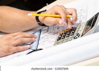 Man working with a calculator and square drawing on blueprints