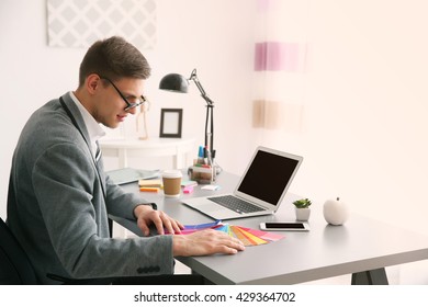 Homme travaillant avec des échantillons de couleurs au bureau