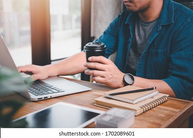 A Man Working With Computer Laptop And In His Hand He Still Holds A Cup Of Coffee.concept Work Form Home, Stay At Home.