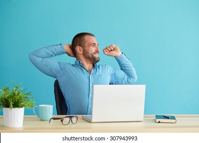 Man Working At Desk In Office Stretching His Back At Desk