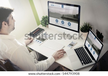 man working with devices with responsive web design. All screen graphics are made up.
