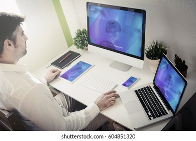 Man Working With Devices With Responsive Website. All Screen Graphics Are Made Up.