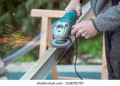 A man working with electric grinder tool on Steel beam. sparks flying. Electric grinding. Remove rust