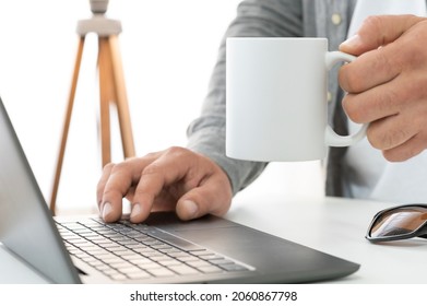 Man Working In Fancy Office And Drink Tea From 10 Oz White Ceramic Mug. White Cup Copy Space Mockup For Your Design. Business, Working At Home Concept