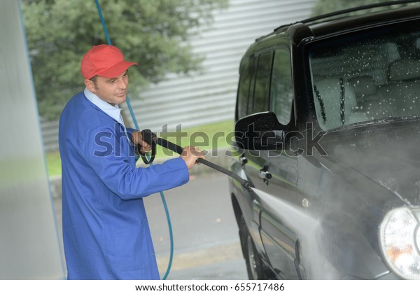 man\
working with high pressure washer to clean a\
car