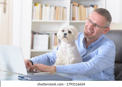 Man working at home and holding his liitle dog.