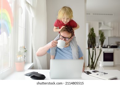 Man is working from home with laptop during quarantine. Home office and parenthood at same time. Exhausted parent with hyperactive child. Chaos with kids during isolation