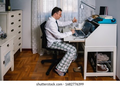 Mann, der von zu Hause aus mit Laptop mit Hemd, Krawatte und Schlafanzug arbeitet