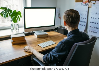 Man working from home office. Computer with blank empty screen for copy space and information. Businessman from behind shoulder view. A creative entrepreneur