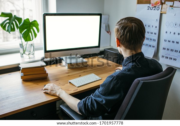 Man working from home office.\
Computer with blank empty screen for copy space and information.\
Businessman from behind shoulder view. A creative\
entrepreneur