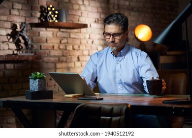 Man Working From Home In Home Office With Tablet Computer At Desk In Trendy Room.