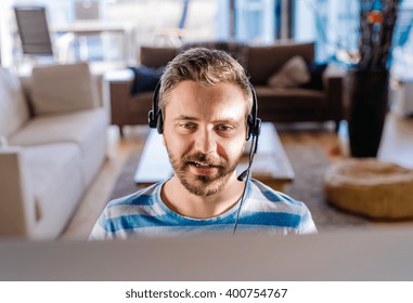 Man Working From Home On Computer, Wearing Headset