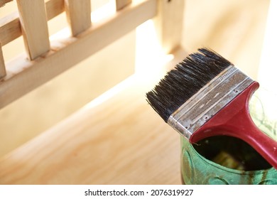 Man Working At Home Varnishing A Wooden Chair With A Brush And Varnish. Man Composing His Chair Himself.