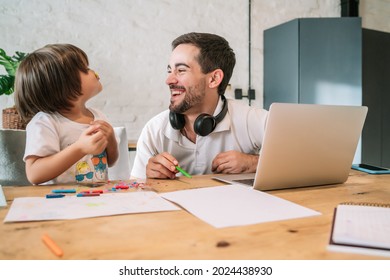 Man working from home while taking care of his son.