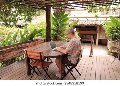 Man working from hotel at the beach. Concept for digital nomad, work from anywhere, work and travel.