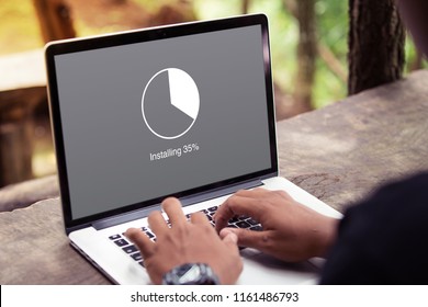 Man working and Installing update with circle load percentage waiting indicator concept on the laptop / computer screen at the park / outdoor