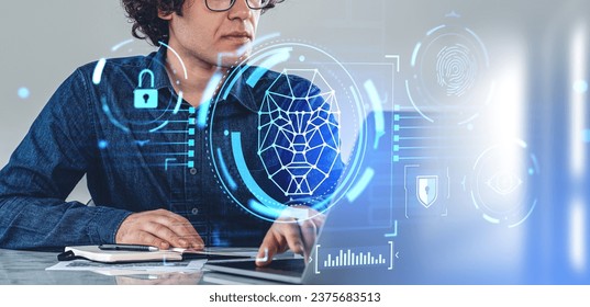 Man working with laptop and notes, biometric scanning and face id. Digital hud hologram with fingerprint, padlock, eye tracking and circuit board. Concept of cyber security and online protection - Powered by Shutterstock - Get 15% off with code: PIKWIZARD15