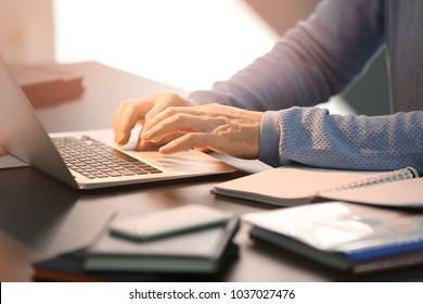 Mann, der mit Laptop am Tisch arbeitet